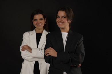 Photo of Portrait of beautiful twin sisters on black background