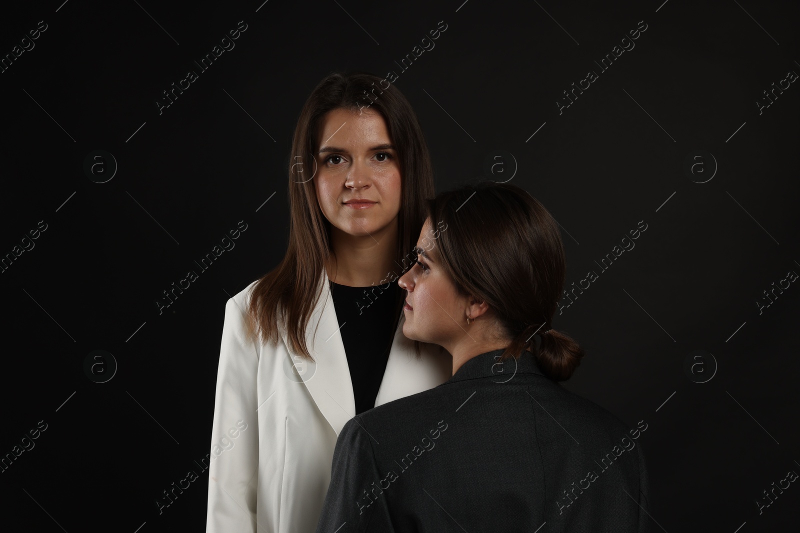 Photo of Portrait of beautiful twin sisters on black background