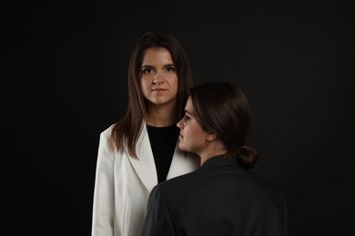 Photo of Portrait of beautiful twin sisters on black background