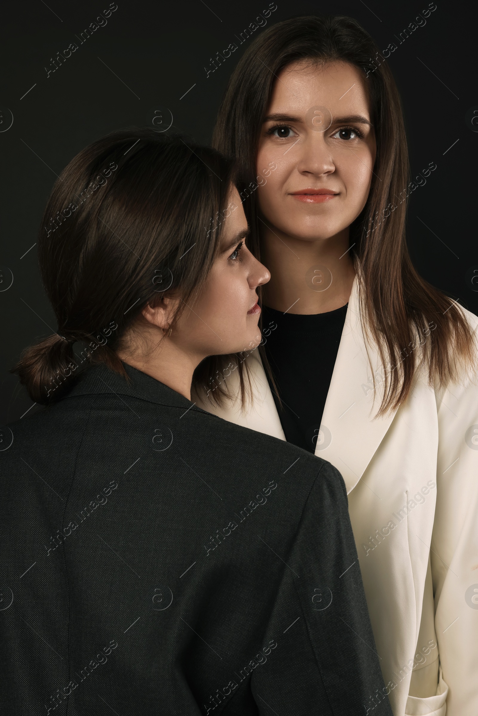 Photo of Portrait of beautiful twin sisters on black background