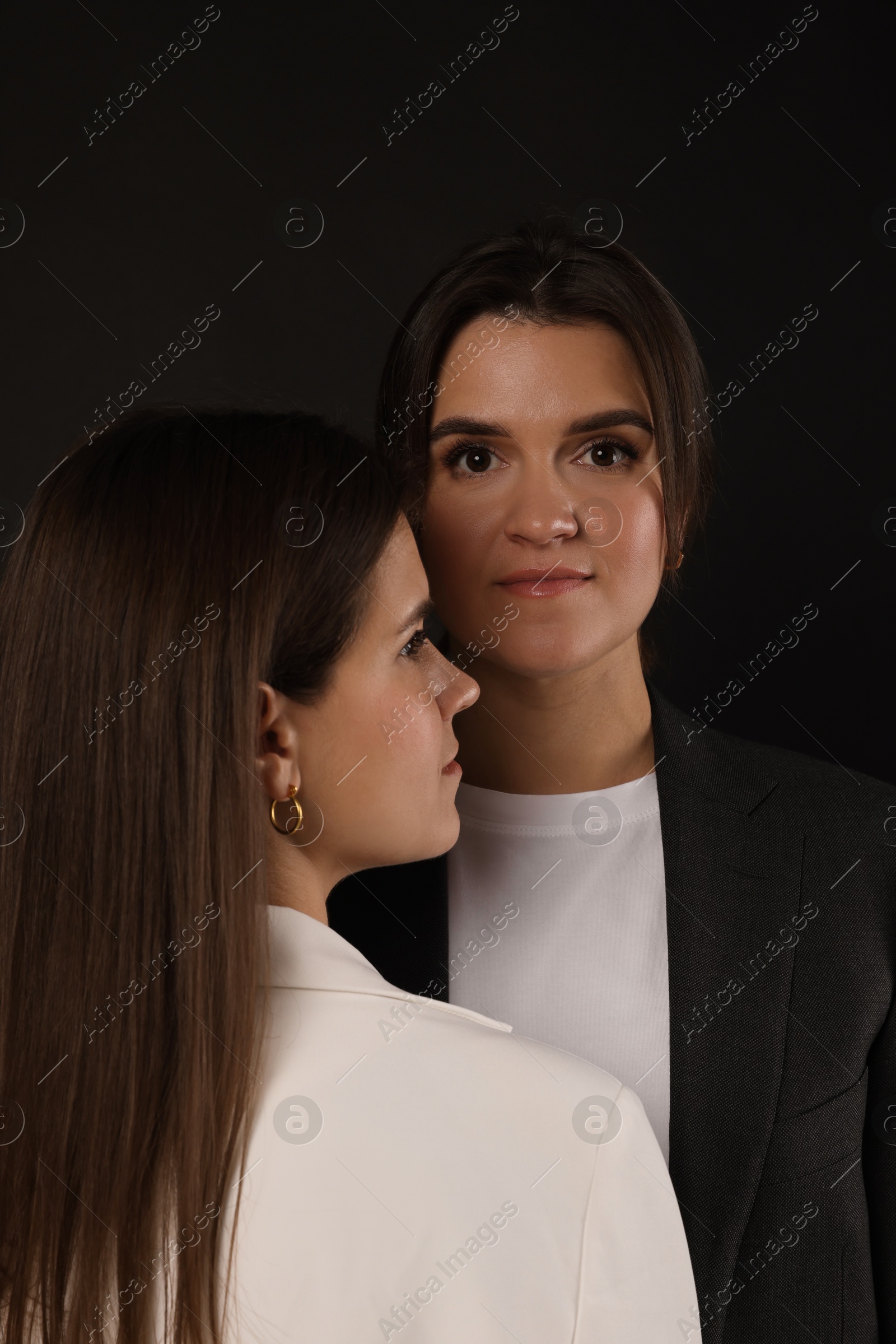 Photo of Portrait of beautiful twin sisters on black background