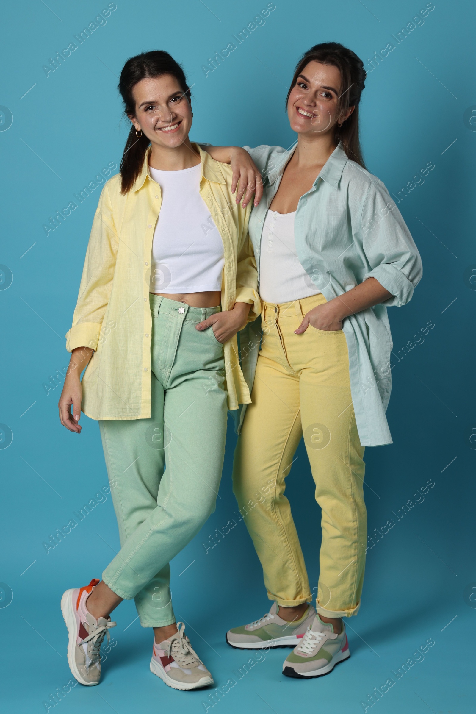 Photo of Portrait of beautiful twin sisters on light blue background