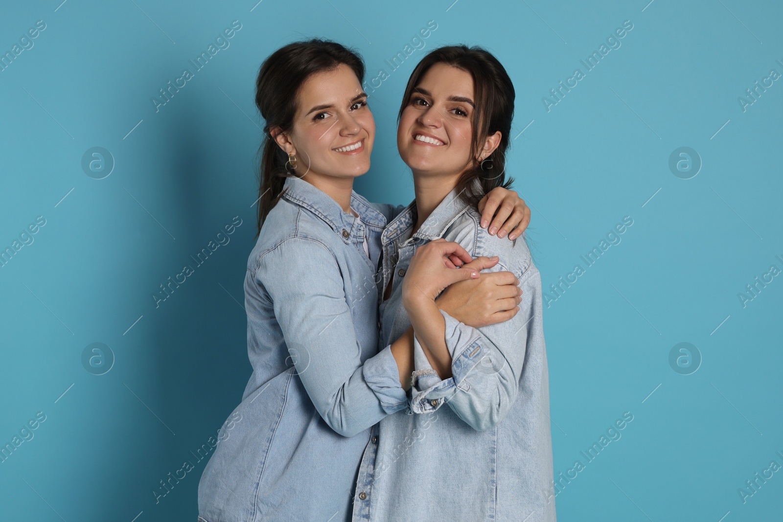 Photo of Portrait of beautiful twin sisters on light blue background