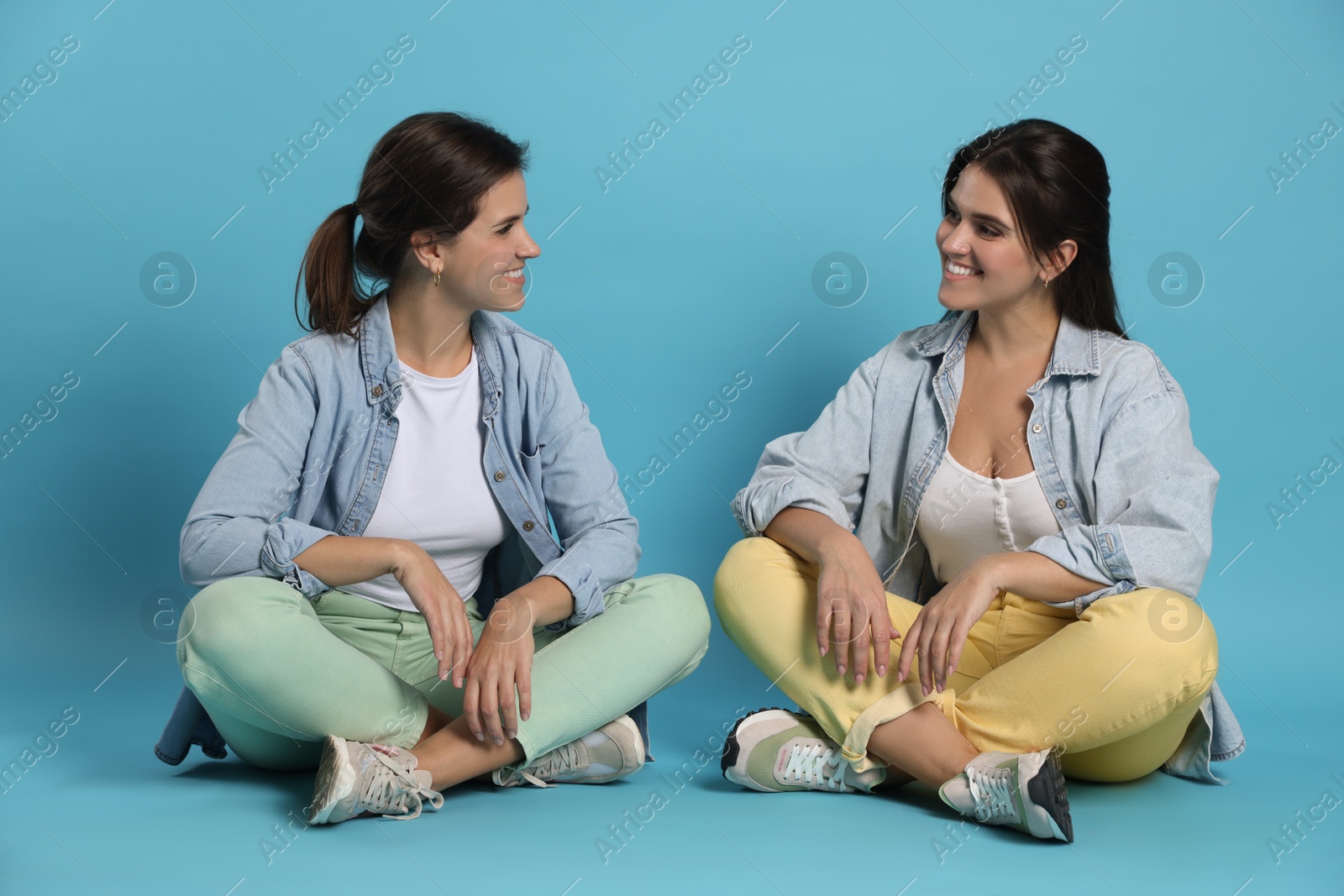 Photo of Portrait of beautiful twin sisters on light blue background