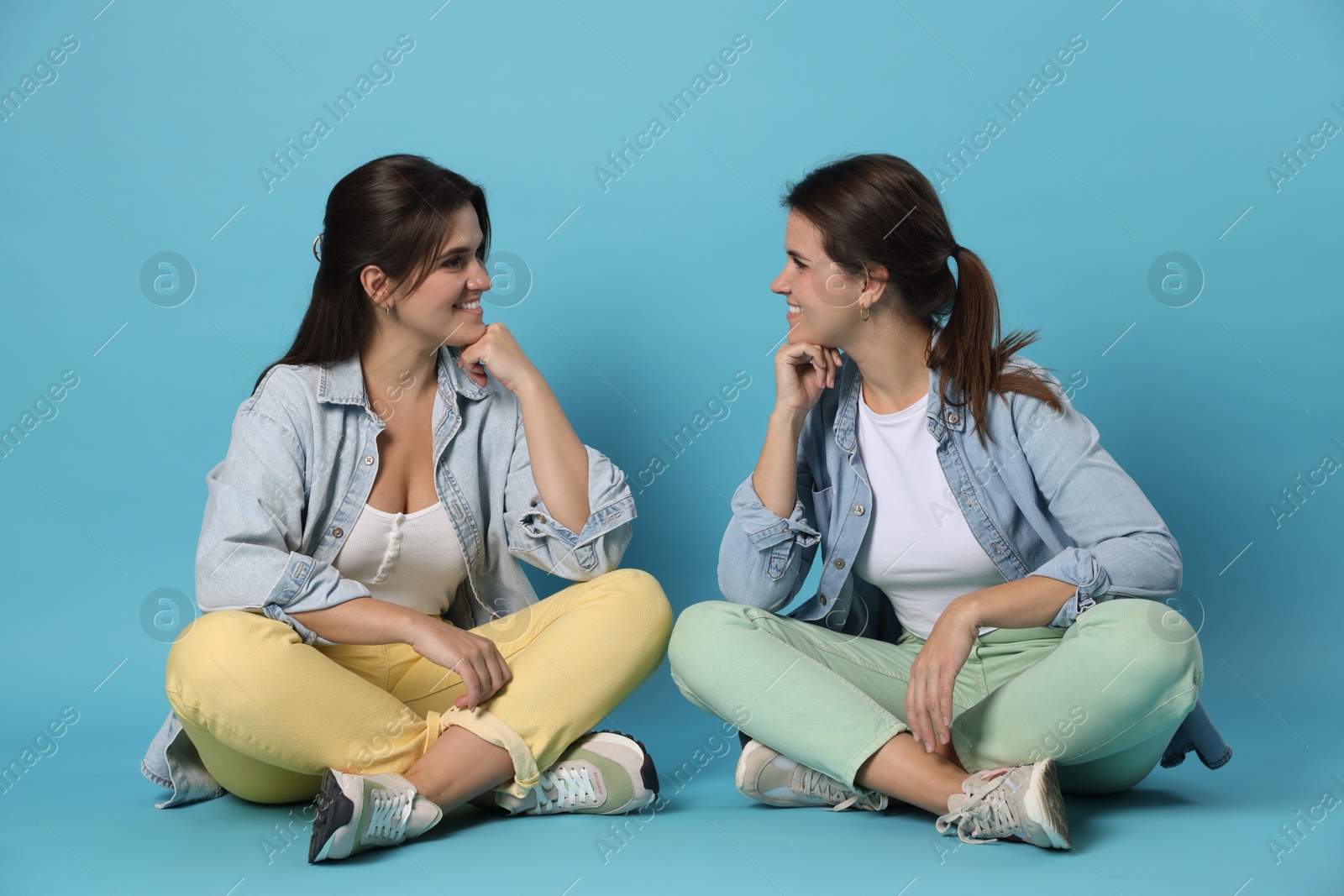 Photo of Portrait of beautiful twin sisters on light blue background