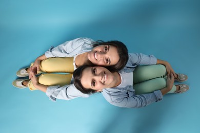 Photo of Portrait of beautiful twin sisters on light blue background, top view