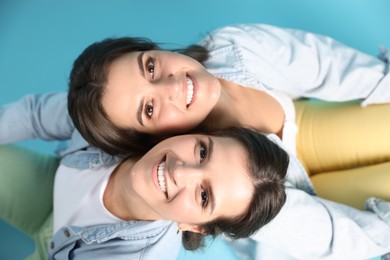 Photo of Portrait of beautiful twin sisters on light blue background, top view