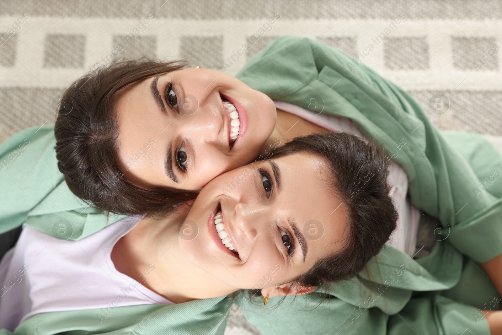 Photo of Portrait of beautiful twin sisters at home, top view