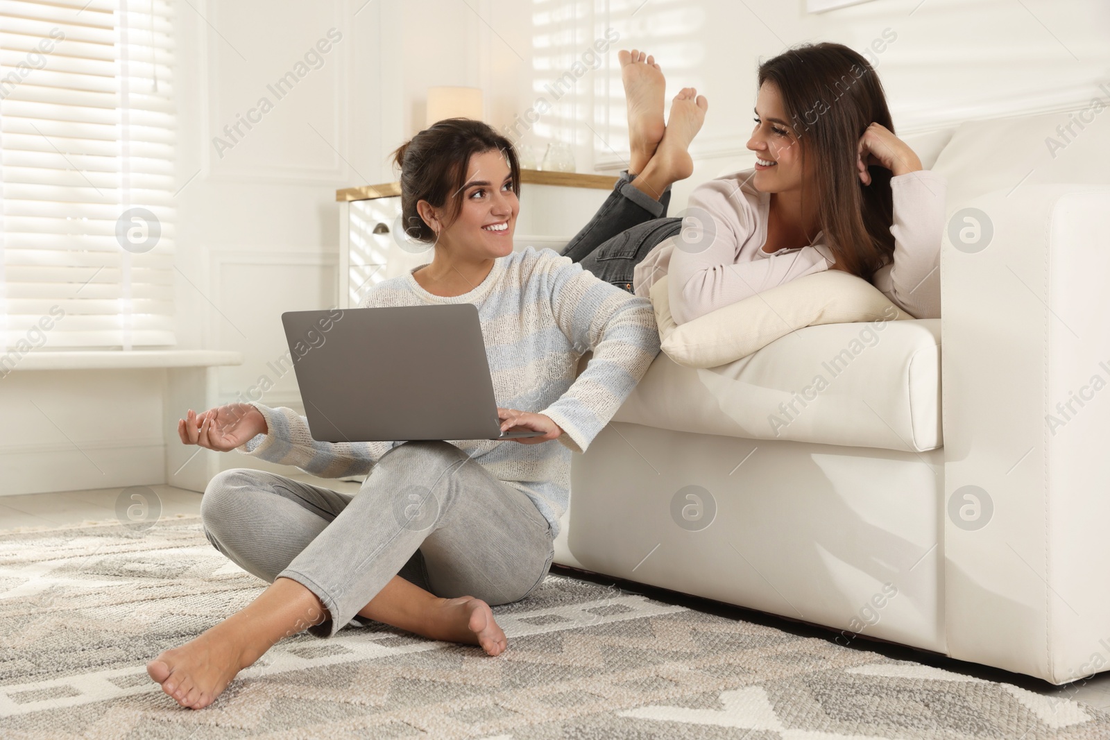 Photo of Beautiful twin sisters with laptop at home