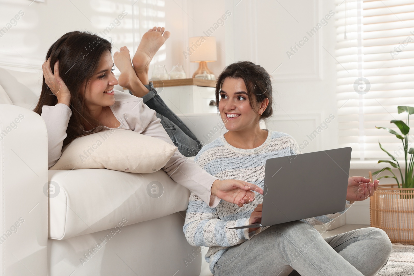 Photo of Beautiful twin sisters with laptop at home