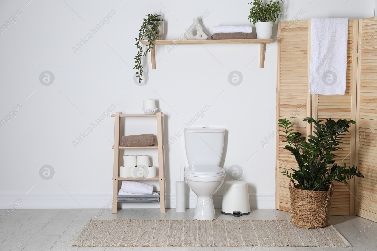 Photo of Folding screen, toilet bowl and houseplants in restroom. Interior design