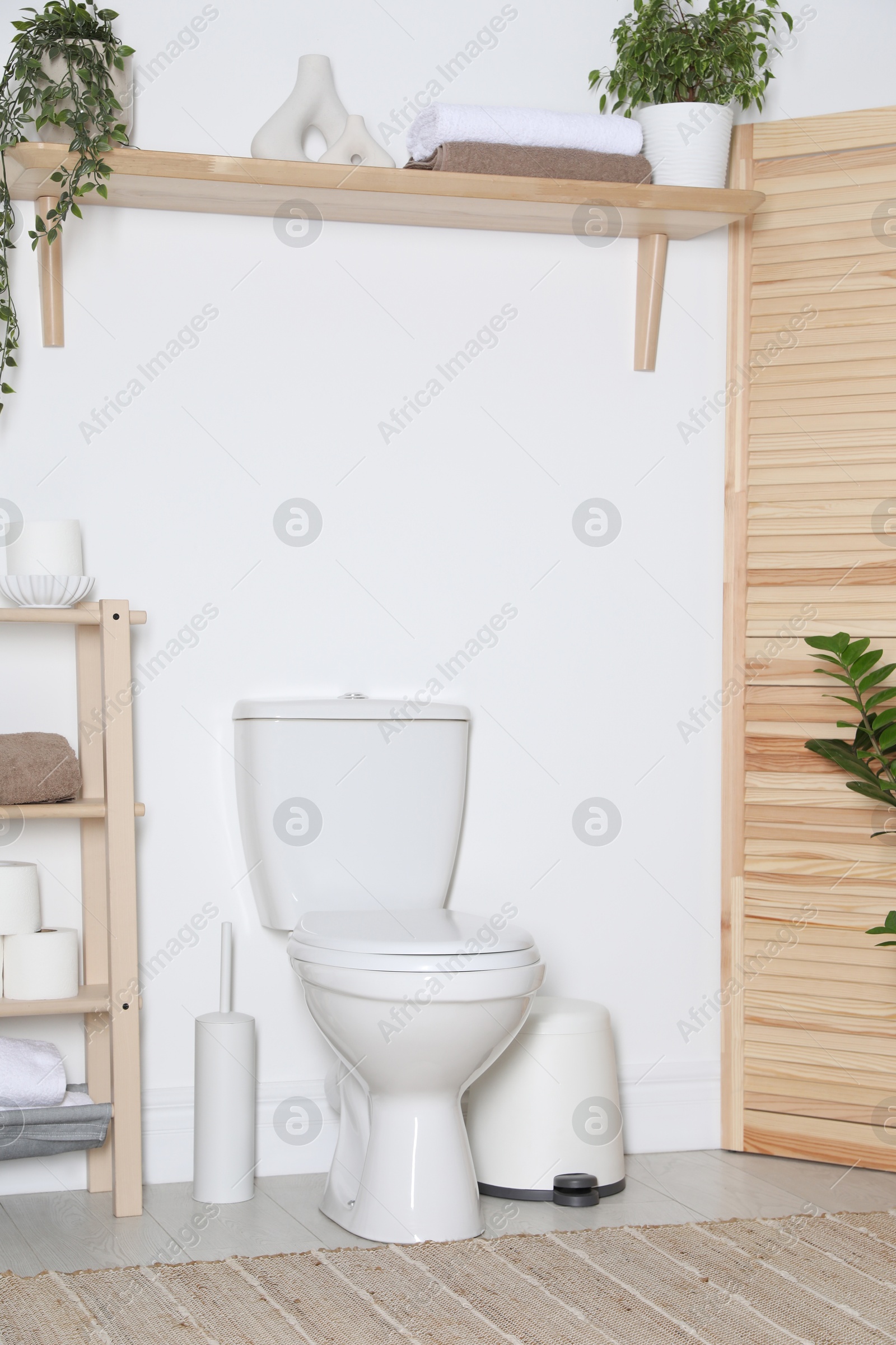 Photo of Folding screen, toilet bowl and houseplants in restroom. Interior design