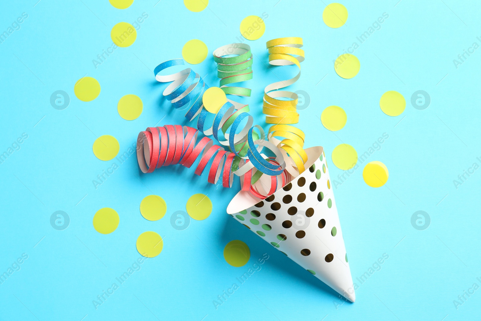 Photo of Party hat with confetti and streamers on light blue background, flat lay