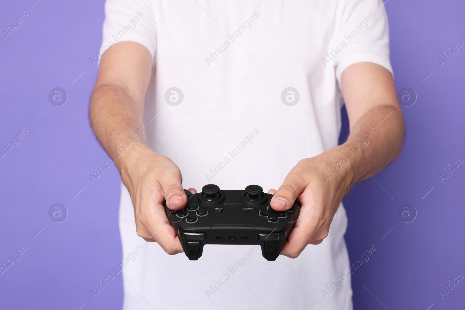 Photo of Man playing video games with controller on violet background, closeup