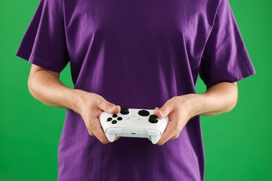 Photo of Man playing video games with controller on green background, closeup