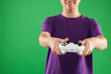 Photo of Man playing video games with controller on green background, closeup. Space for text