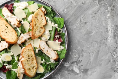 Photo of Tasty Caesar salad with chicken on gray textured table, top view. Space for text