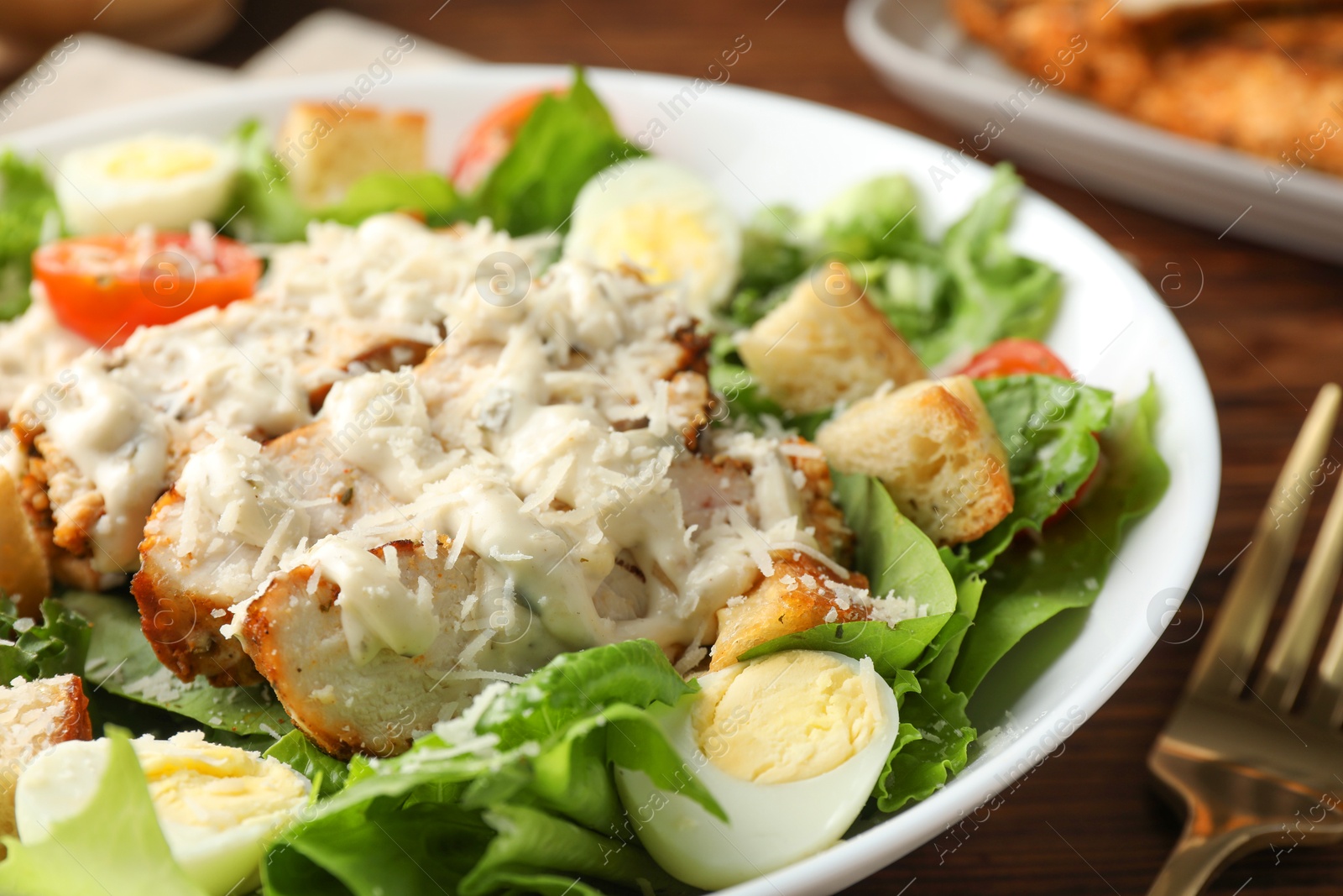 Photo of Tasty Caesar salad with chicken in bowl on table, closeup