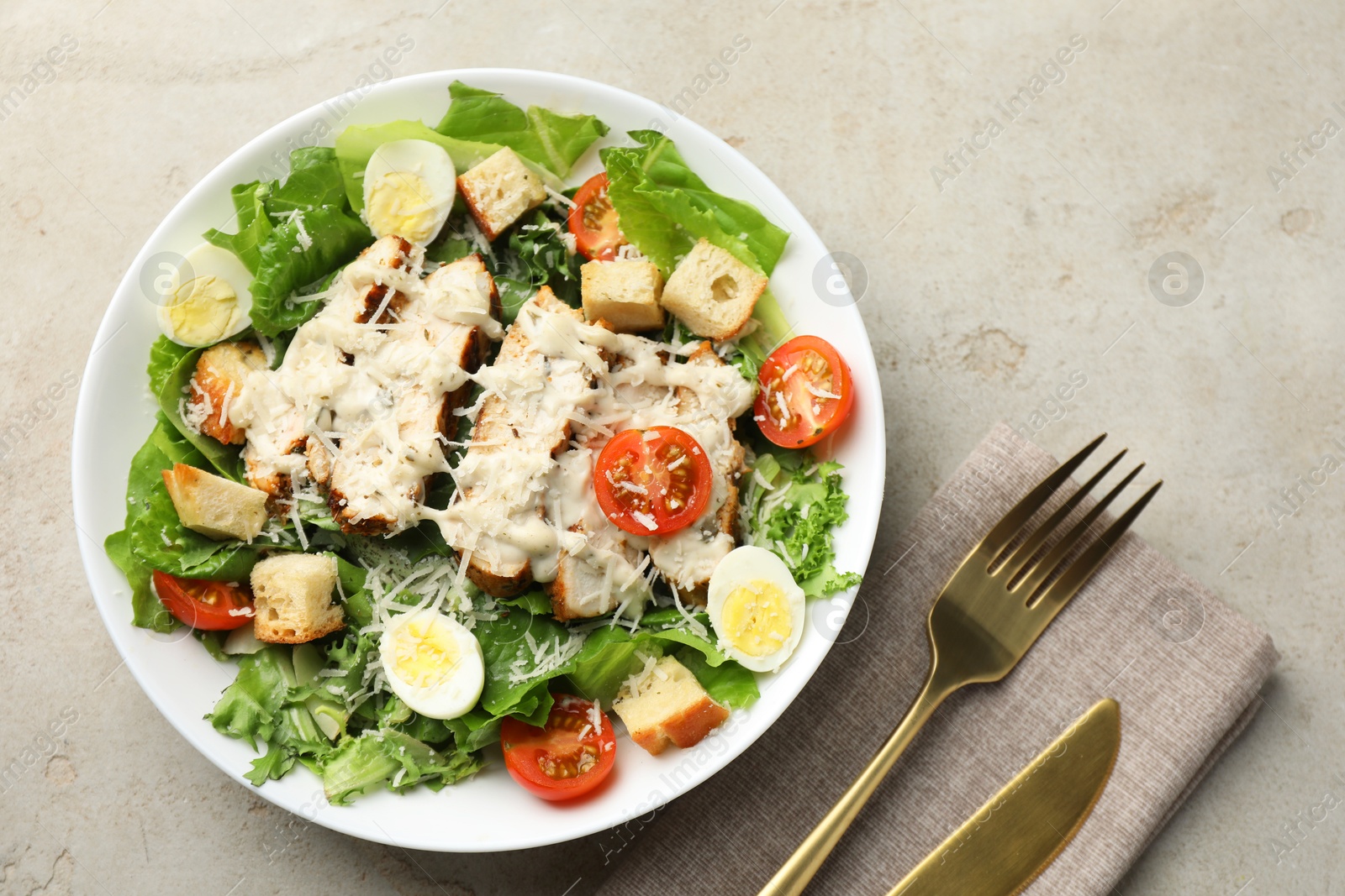 Photo of Tasty Caesar salad with chicken and tomatoes in bowl served on gray textured table, flat lay