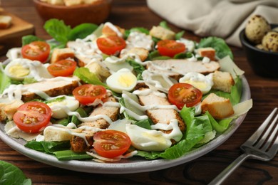 Photo of Delicious Caesar salad with chicken on wooden table, closeup