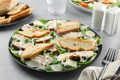 Photo of Delicious Caesar salad with chicken on grey textured table, closeup