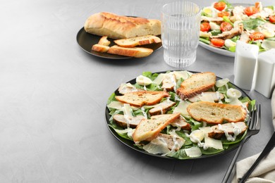 Photo of Delicious Caesar salad with chicken on grey textured table. Space for text