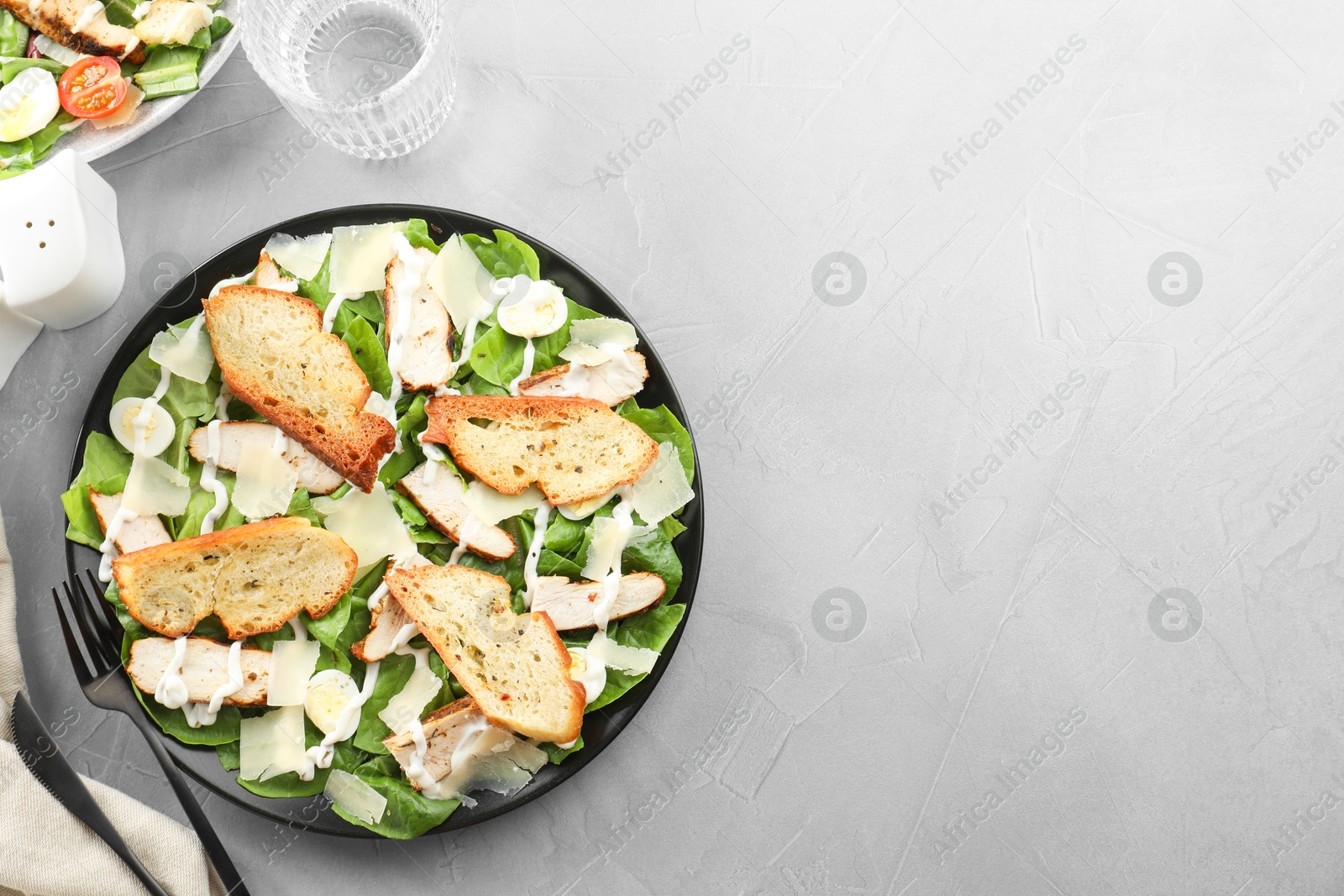 Photo of Delicious Caesar salad with chicken served on grey textured table, flat lay. Space for text