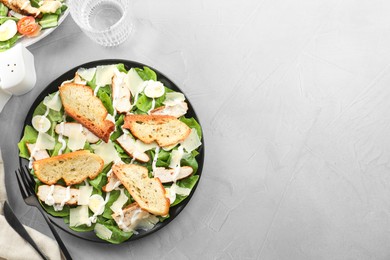 Photo of Delicious Caesar salad with chicken served on grey textured table, flat lay. Space for text