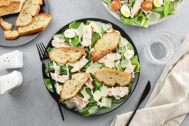 Photo of Delicious Caesar salad with chicken served on grey textured table, flat lay