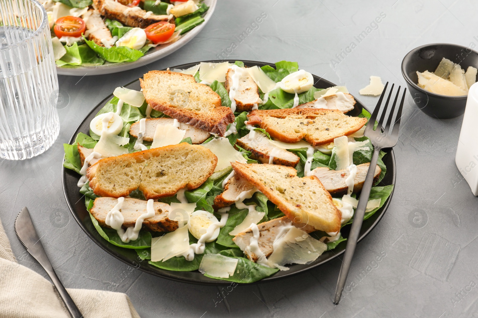 Photo of Delicious Caesar salad with chicken on grey textured table