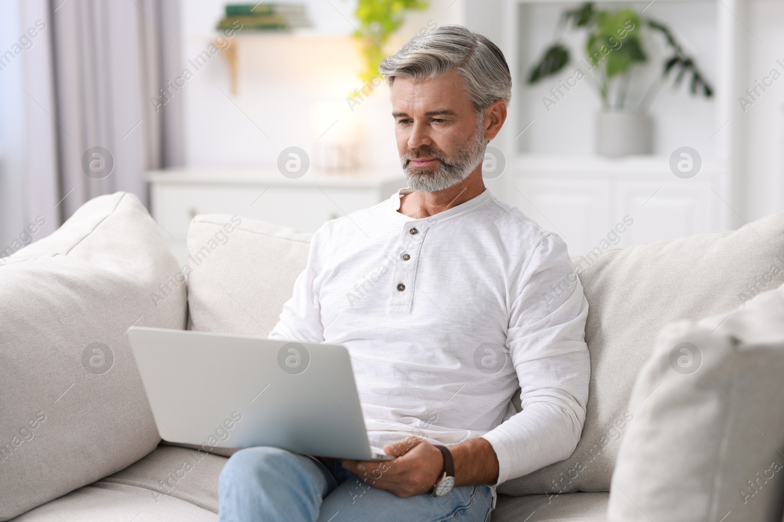 Photo of Middle aged man with laptop on sofa at home