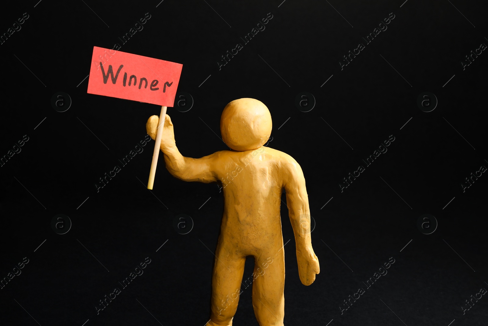 Photo of Human figure holding wooden stick with word Winner on black background