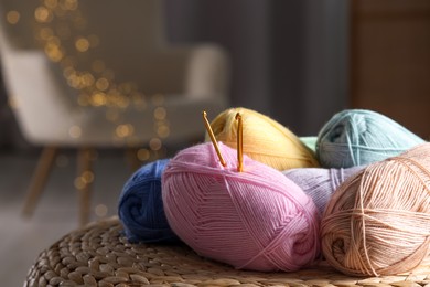 Photo of Knitting material. Skeins of soft yarn and crochet hooks on wicker surface indoors, closeup