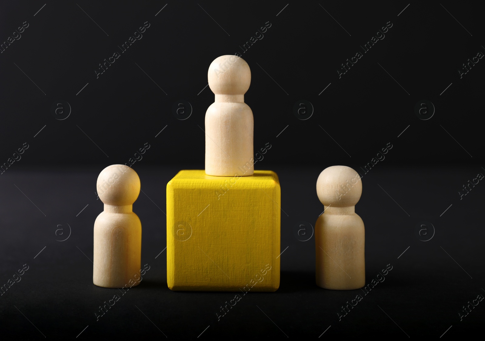 Photo of Winner. One wooden figure on podium among others against black background