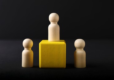 Photo of Winner. One wooden figure on podium among others against black background