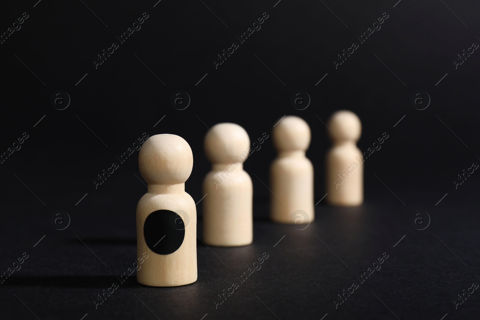 Photo of Winner. Piece with dark dot among wooden ones against black background, selective focus