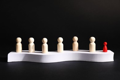 Photo of Winner. Red piece among wooden ones on podium against black background