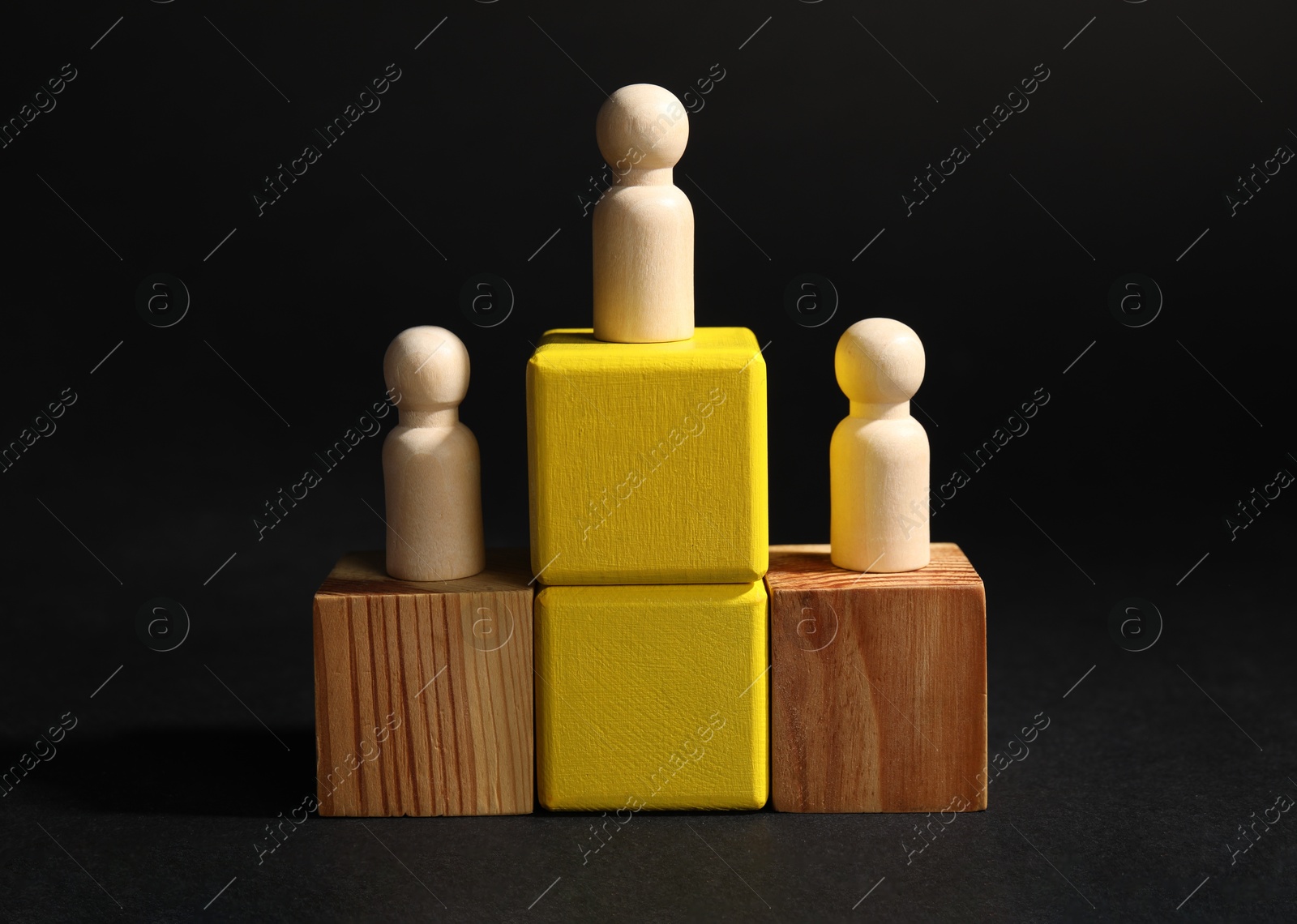 Photo of Winner. Wooden figures on cubes against black background