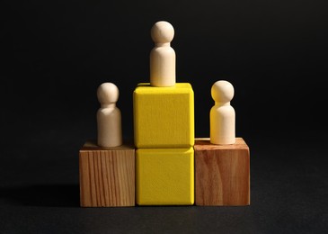 Photo of Winner. Wooden figures on cubes against black background