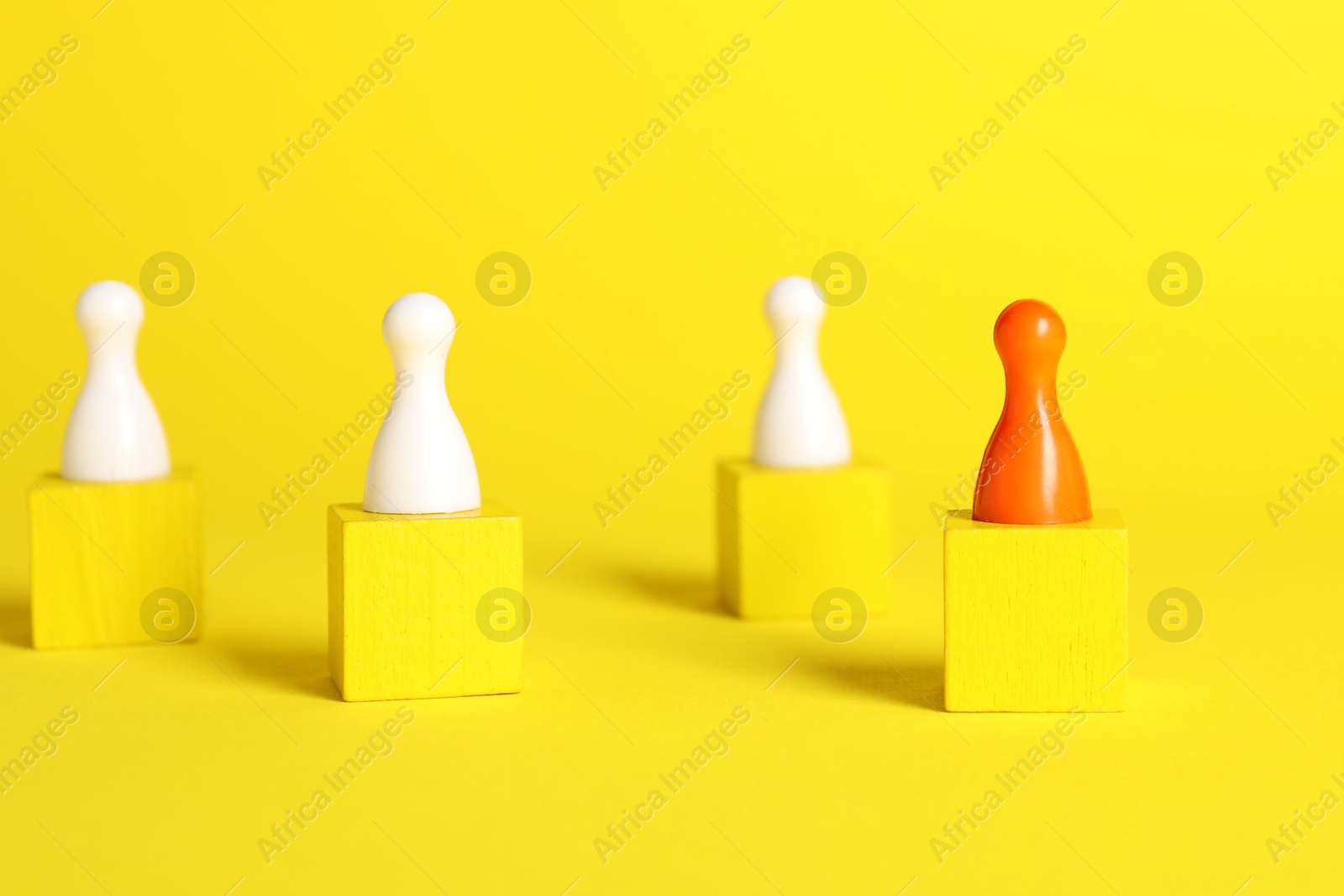 Photo of Winner concept. Red piece among wooden ones on cubes against yellow background, selective focus