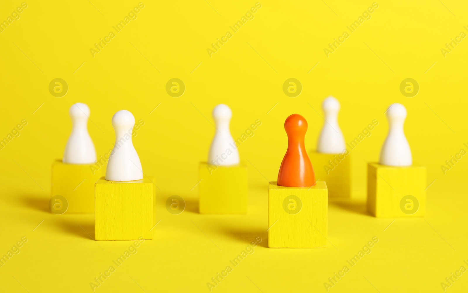 Photo of Winner concept. Red piece among wooden ones on cubes against yellow background, selective focus