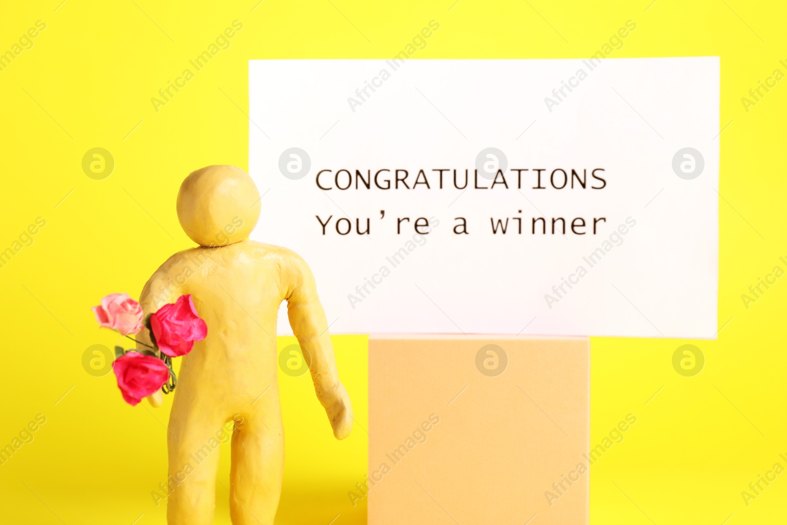 Photo of Human figure holding bouquet of flowers and card with phrase Congratulations You`re Winner against yellow background