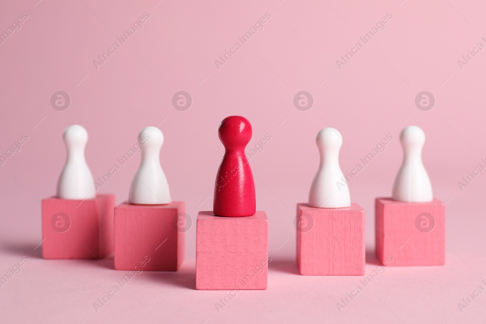 Photo of Winner. Red piece among wooden ones on cubes against pink background