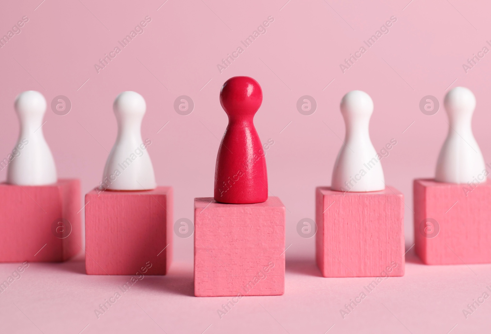 Photo of Winner. Red piece among wooden ones on cubes against pink background