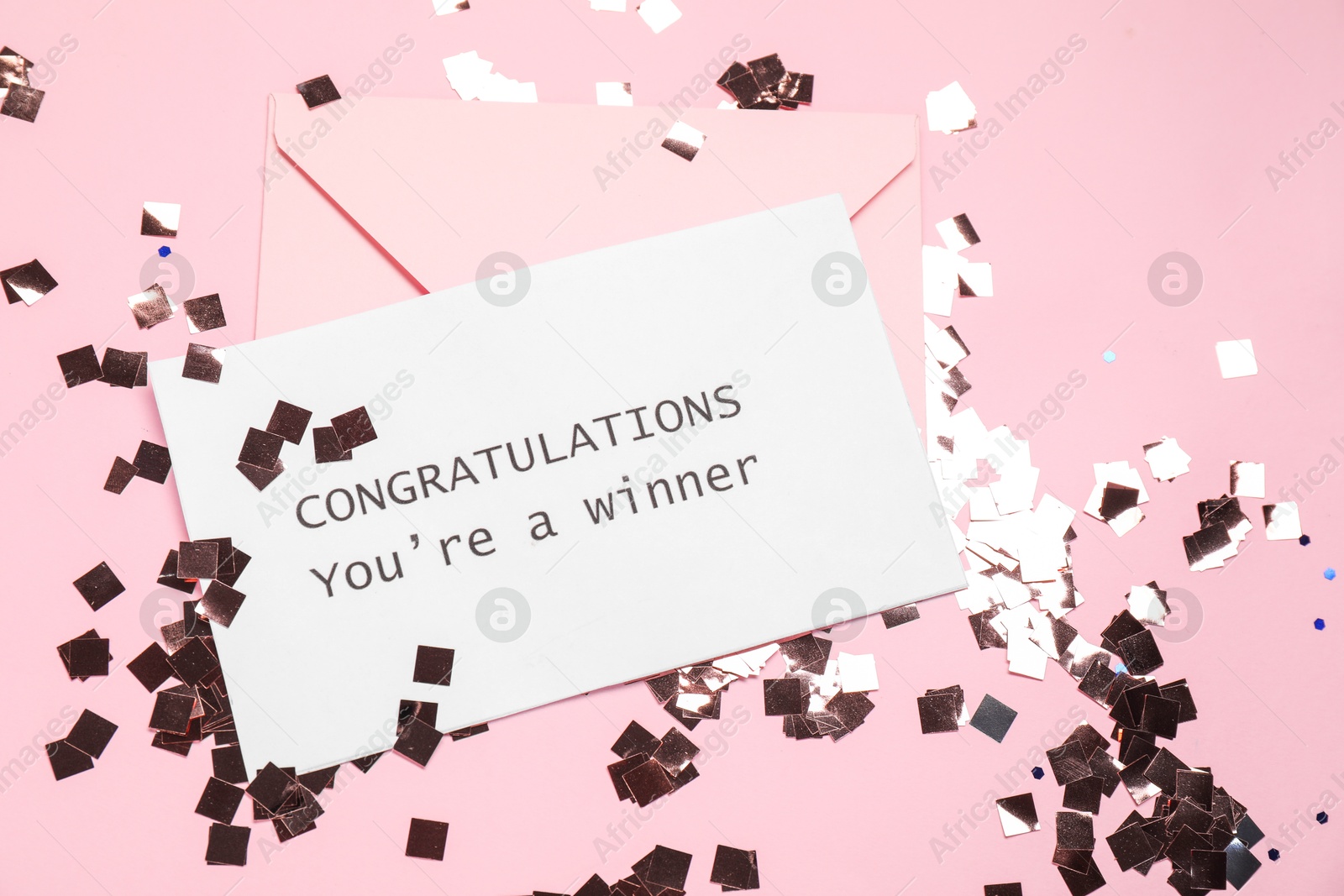 Photo of Card with phrase Congratulations You`re Winner, envelope and confetti on pink background, flat lay