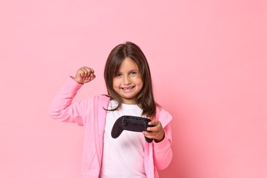 Photo of Happy little girl with controller on pink background