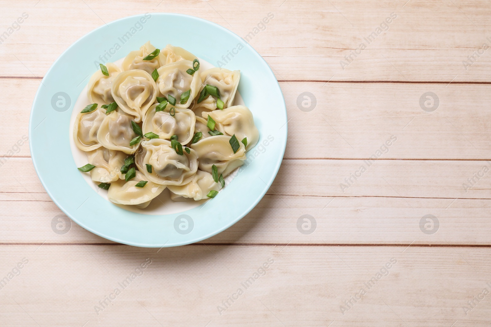 Photo of Delicious pelmeni with green onion on white wooden table, top view. Space for text