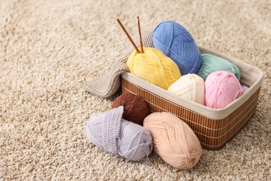 Photo of Colorful yarns, crochet sample, hooks and basket on soft carpet, closeup. Space for text