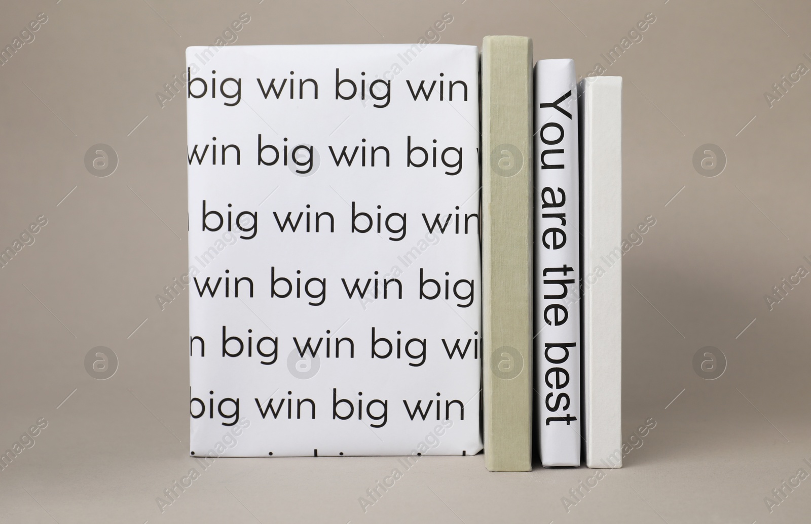 Photo of White books with phrases You are the best and Big win between ones on light grey background