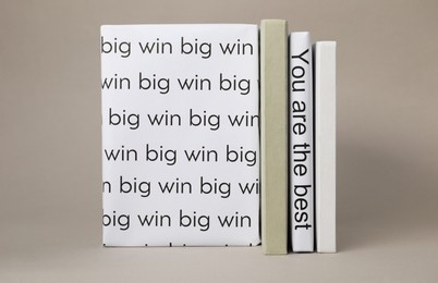 Photo of White books with phrases You are the best and Big win between ones on light grey background